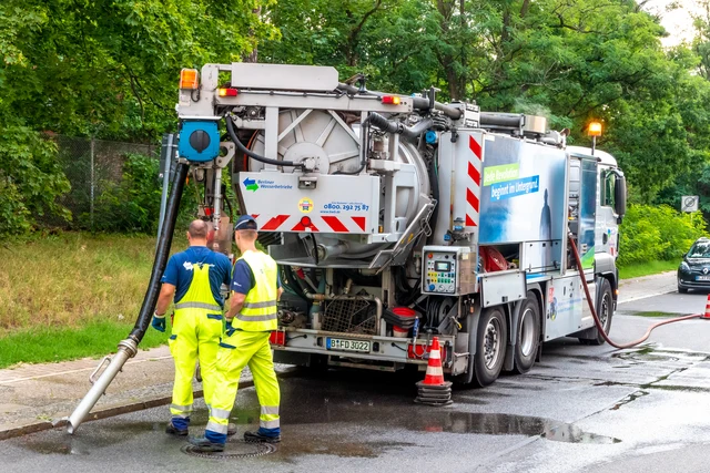 Pracovníci čistí septik pomocí velkého vakuového vozu na ulici.
