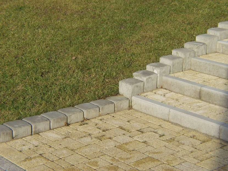 Venkovní schody z betonu a dlažby vedoucí na trávník.