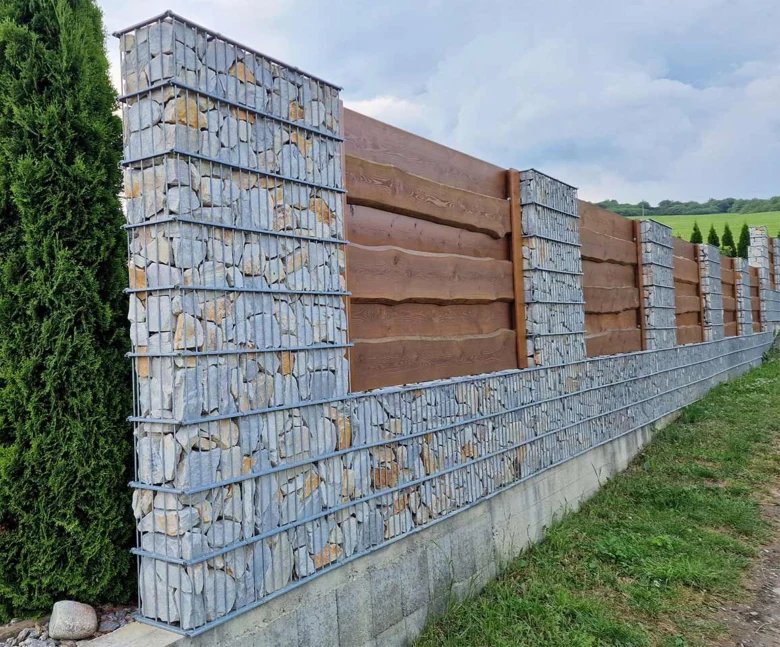 Hotová zeď z gabionů s kamenným plněním na trávníku.