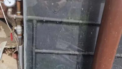 Znečištěný solární kolektor pro ohřev vody na domovní zdi.