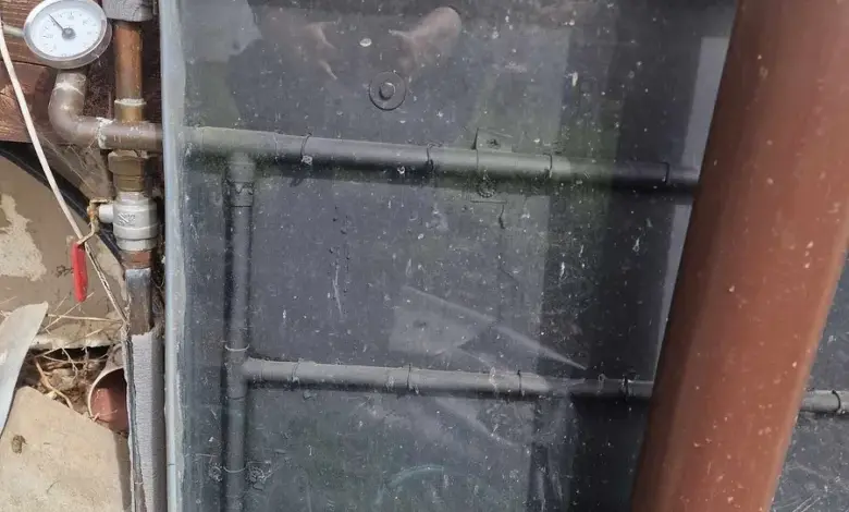 Znečištěný solární kolektor pro ohřev vody na domovní zdi.