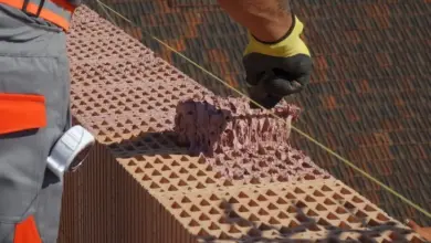 Stavebník nanáší maltu na cihlovou zeď při práci za chladného počasí.