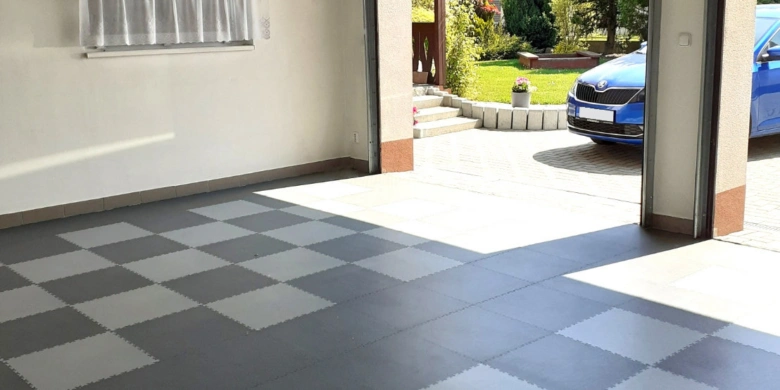 Instalace šedobílých dlaždic do garáže s otevřenou bránou.