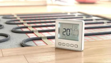 Digitální termostat vedle potrubí podlahového vytápění.