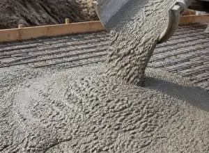 Zelený beton se nalévá na povrch pro stavbu obrubníku.