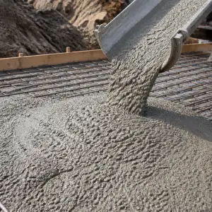 Zelený beton se nalévá na povrch pro stavbu obrubníku.