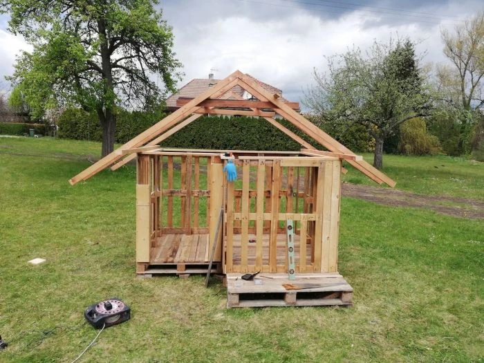 Dřevěný zahradní domek na paletách ve fázi stavby.
