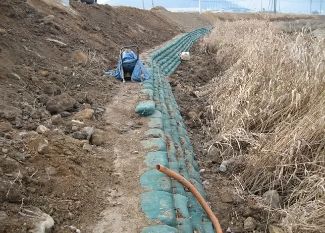 Práce na úpravě svahu s instalací drenážních trubek a terénními změnami.