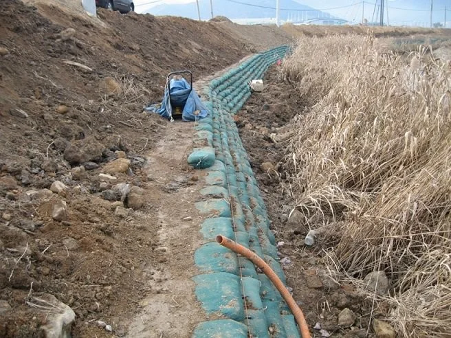 Práce na úpravě svahu s instalací drenážních trubek a terénními změnami.
