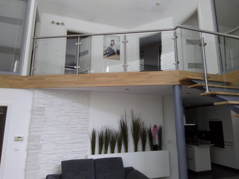 Moderní dřevěné zábradlí s výhledem do obývacího pokoje.