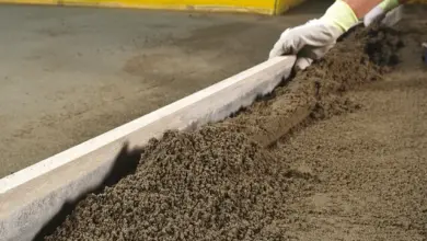 Pracovník vyrovnává čerstvý beton na podlaze pomocí pravítka.