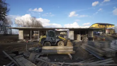Stavba domu na pozemku s výkopovou technikou a stavebními materiály.
