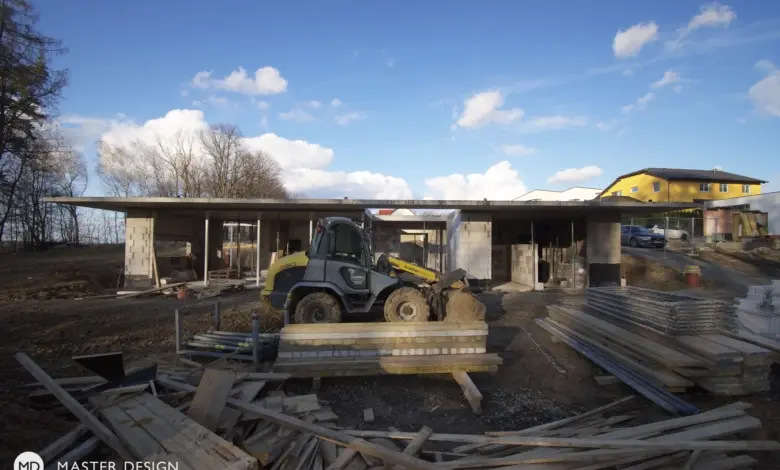 Stavba domu na pozemku s výkopovou technikou a stavebními materiály.
