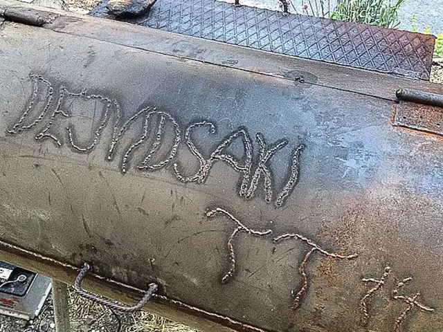 Gril vyrobený z bojleru s vyvařeným textem na povrchu.