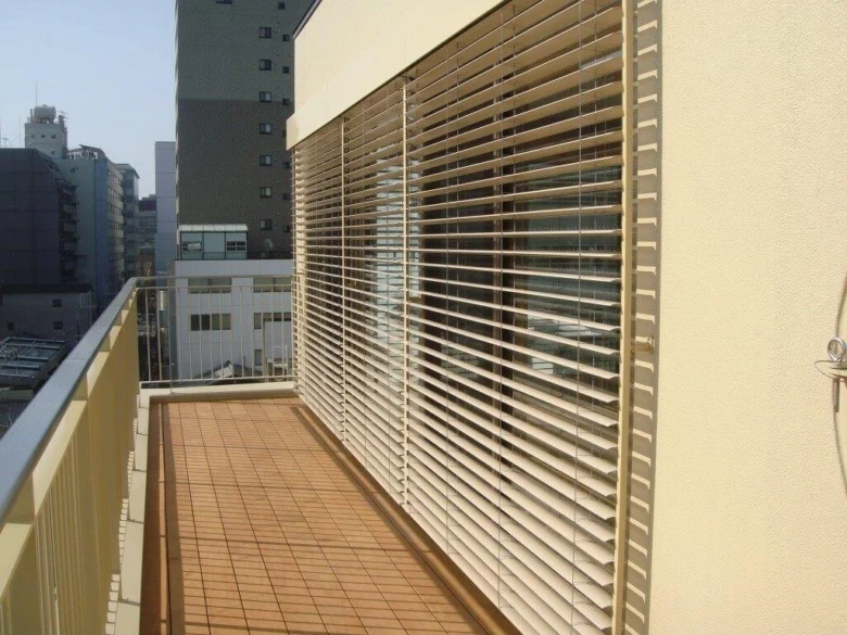 Venkovní žaluzie na balkóně s výhledem do města.
