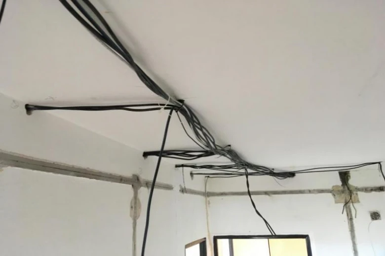 Zamotané elektrické kabely na stropě před rekonstrukcí.