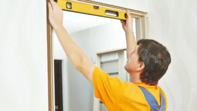 Muž měří vchodové dveře úrovní při instalaci.