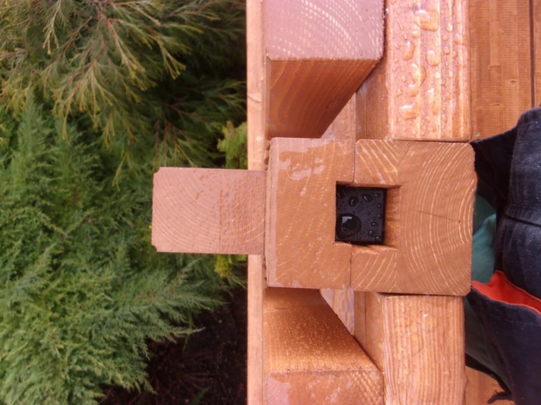 Detail spoje dřevěného balkonu s přírodním okolím.