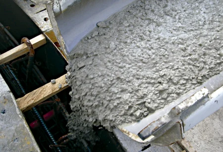 Mokrý beton se nalévá do dřevěného bednění pro základy.