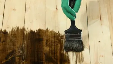 Ruční aplikace tmavého mořidla na světlé dřevěné prkno.