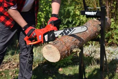 Muž řezí dřevo křovinořezem značky Stihl venku.