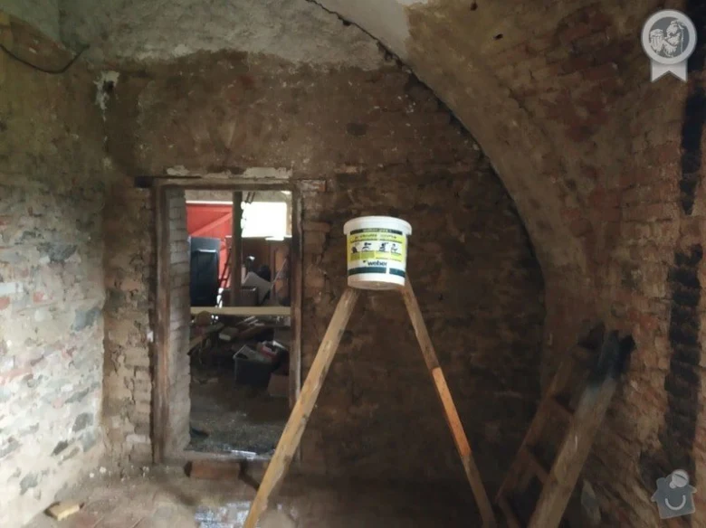 Nerestaurovaný pokoj s viditelnými cihlovými zdmi a stavebními materiály.