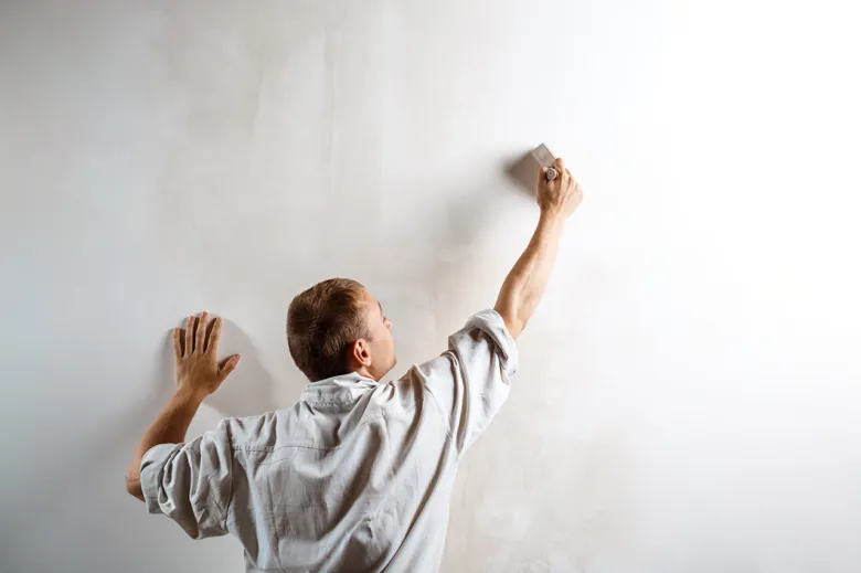 Man painting wall with sponge