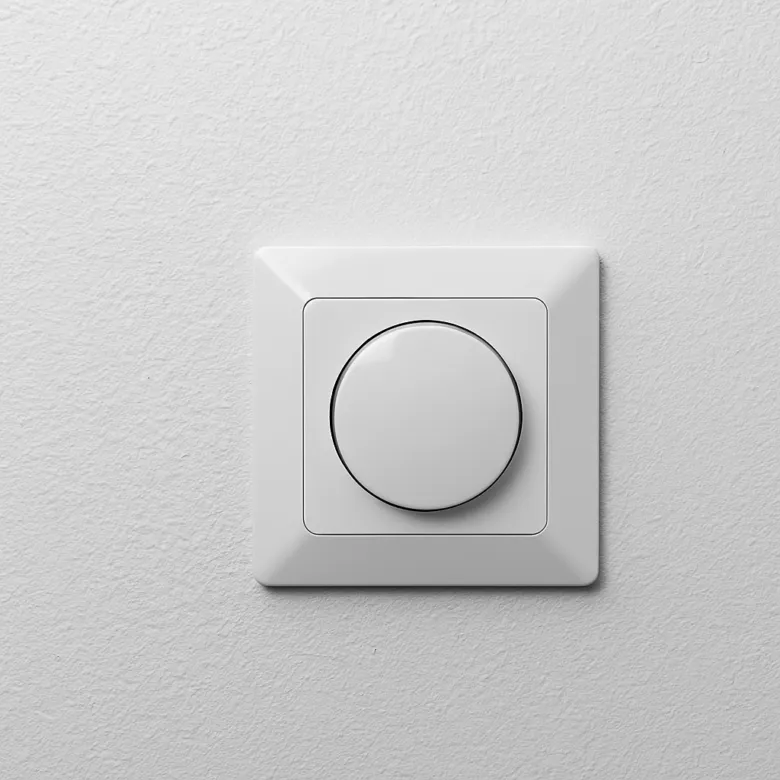 Moderní bílý elektrický vypínač na zdi v interiéru.