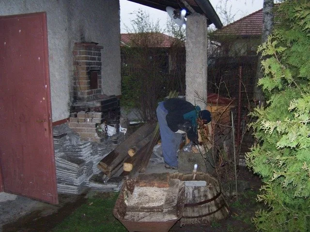 Stavba zděné pergoly u domu s pracovníkem na místě.