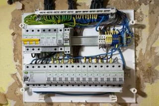 Otevřená elektrická rozvaděč s připojenými vodiči v panelovém bytě.