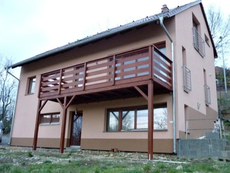 Samostatný dřevěný balkon na dvoupatrovém domě s okeny.