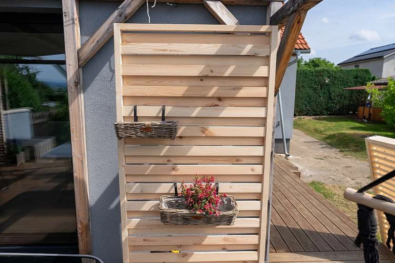 Dřevěný zahradní stínící prkenný panel s košíky na květiny.