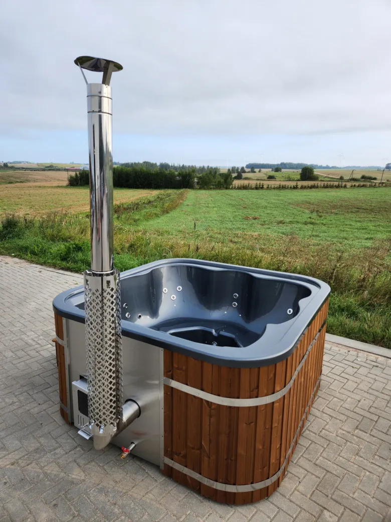 Hot tub z dřeva s komínem na venkovním pozadí.