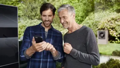 Dva muži se dívají na mobilní telefon v zahradě.