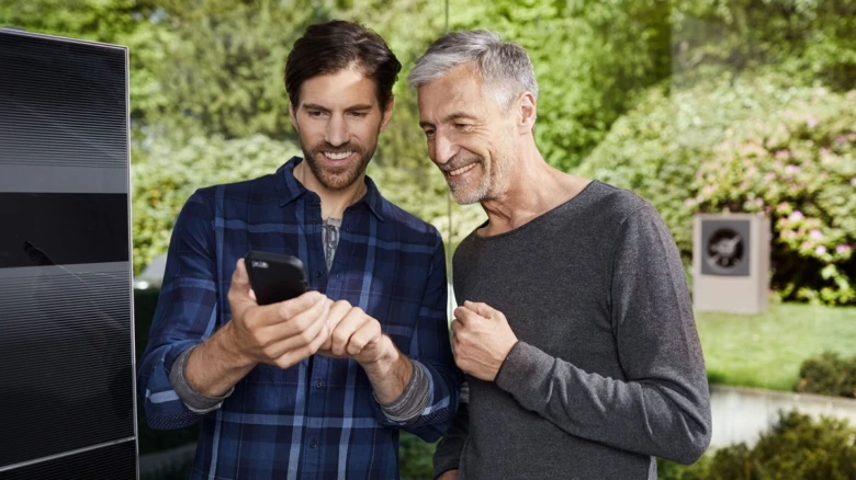 Dva muži se dívají na mobilní telefon v zahradě.