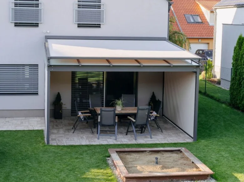 Moderní stínící pergola s nábytkem na zahradě.