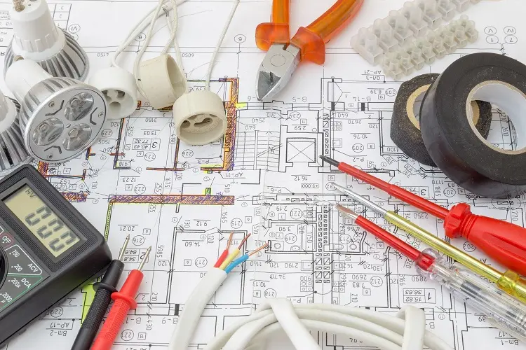 Nástroje pro elektroinstalaci na plánování domu s kabely a žárovkami.