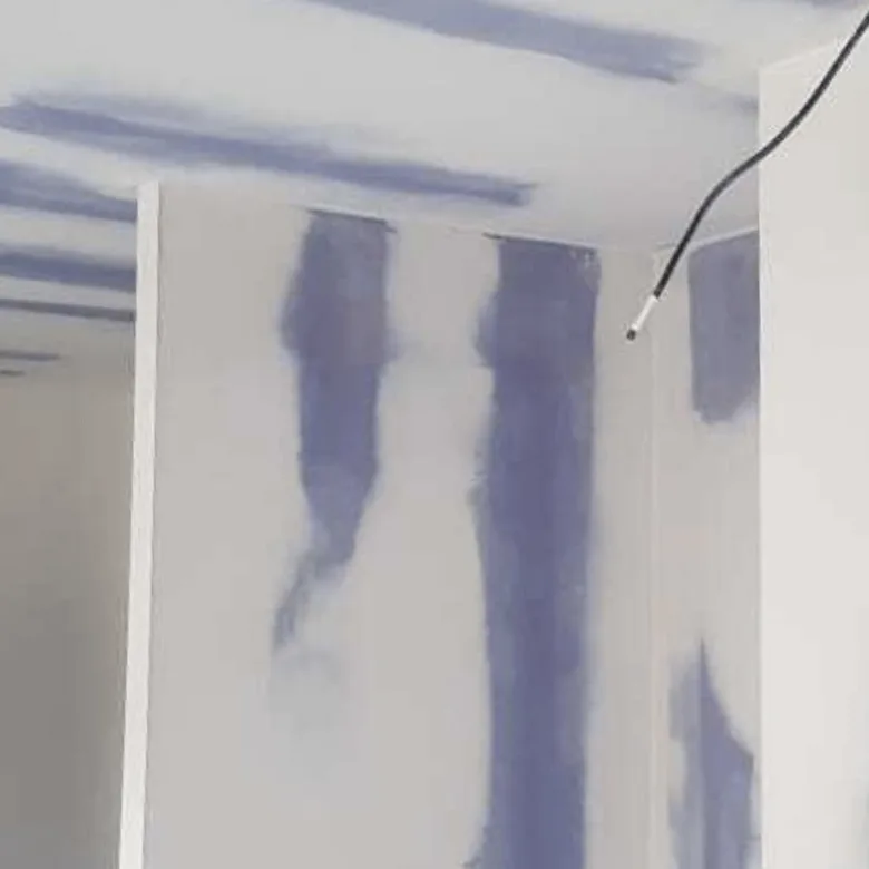 Modrá hmotou se tmelí spoje mezi deskami sádrokartonu v rohu.