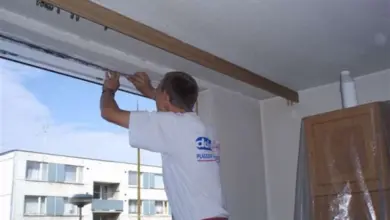 Muž vyměňuje okno v panelovém domě.