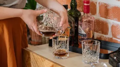 Nalévání whisky do sklenice na dřevěném stole v podkroví.