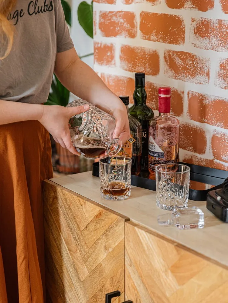 Nalévání whisky do sklenice na dřevěném stole v podkroví.