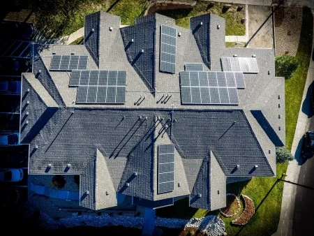 Vzdušný pohled na střechy domů s fotovoltaickými panely.
