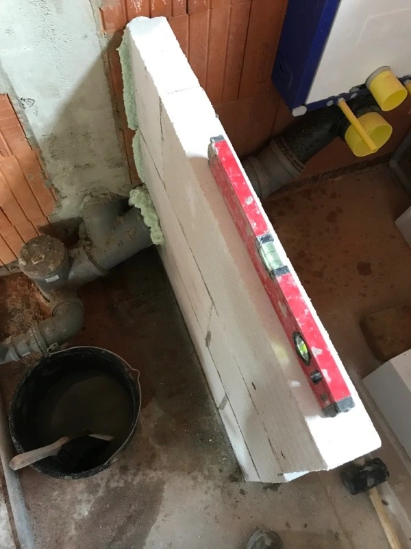 Instalace systému Geberit s pěnovými bloky na cihlové zdi.