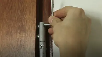 Ruka upravuje pant dveří pomocí šestihranného klíče.