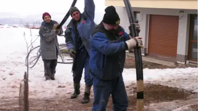 Muži instalují hadici pro vrt tepelného čerpadla.