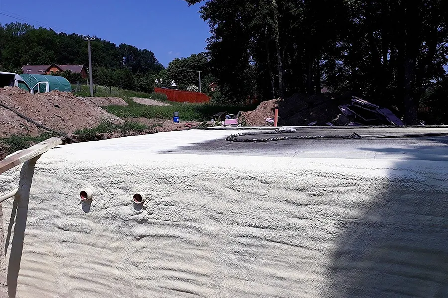 Bílá izolace základové stěny s vývody pro potrubí.