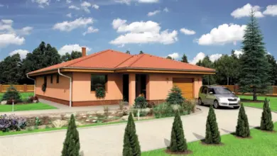 Moderní bungalov s garáží v tvaru písmene U na pozadí zelené zahrady.