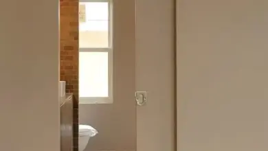 Úzká koupelna viditelná skrz dveře v chodbě.