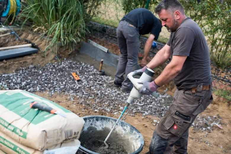 Muž míchá beton z pytle pomocí elektrického mixru.