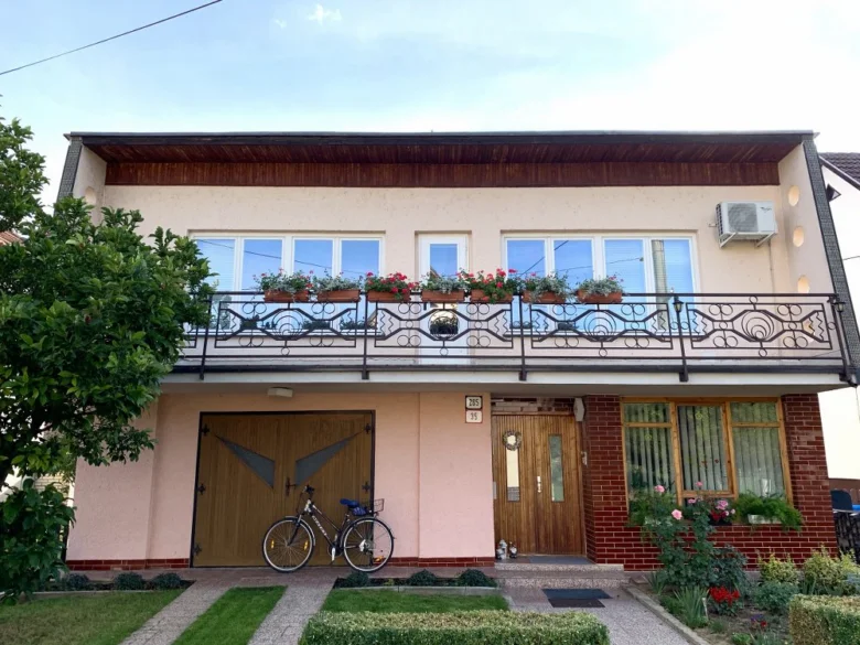 Dvoupatrový dům s balkónem a květinami na oknech.